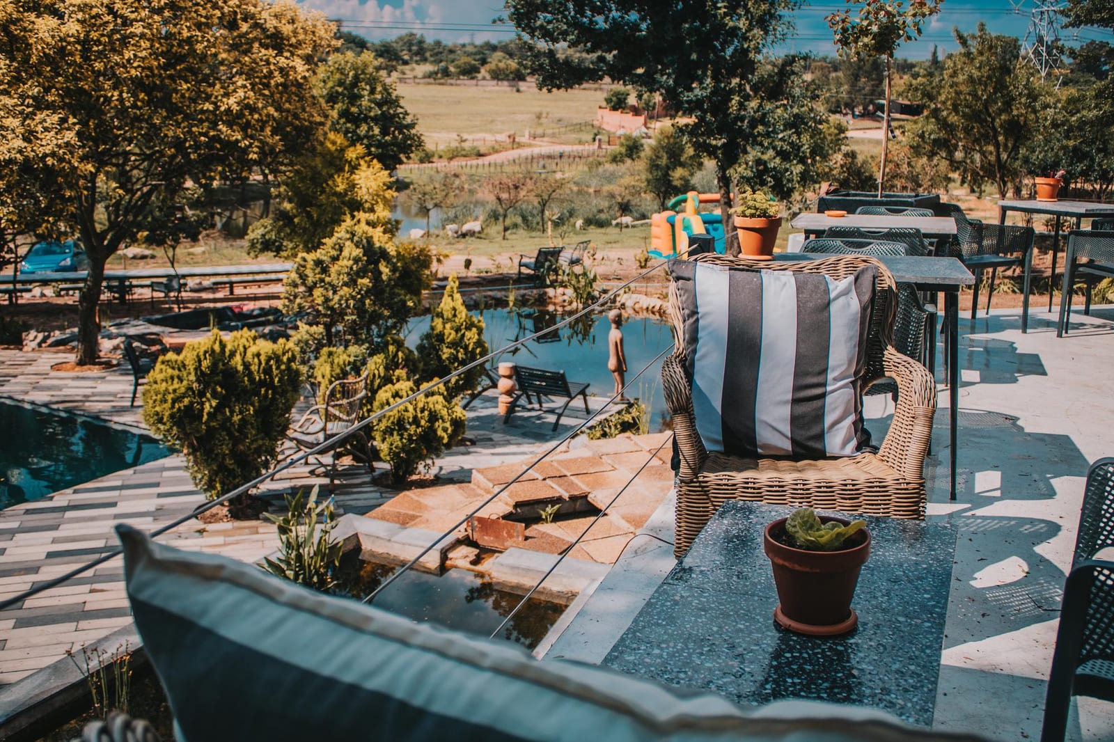 Poltronas de vime com almofadas em um pátio ensolarado com vista para o jardim